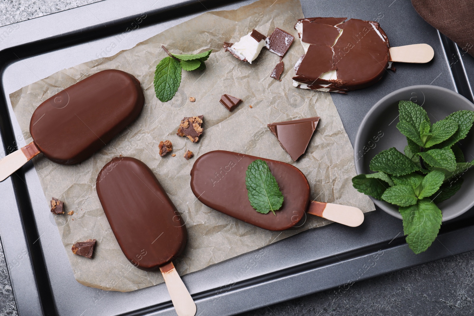 Photo of Glazed ice cream bars, fresh mint and chocolate on baking tray, flat lay