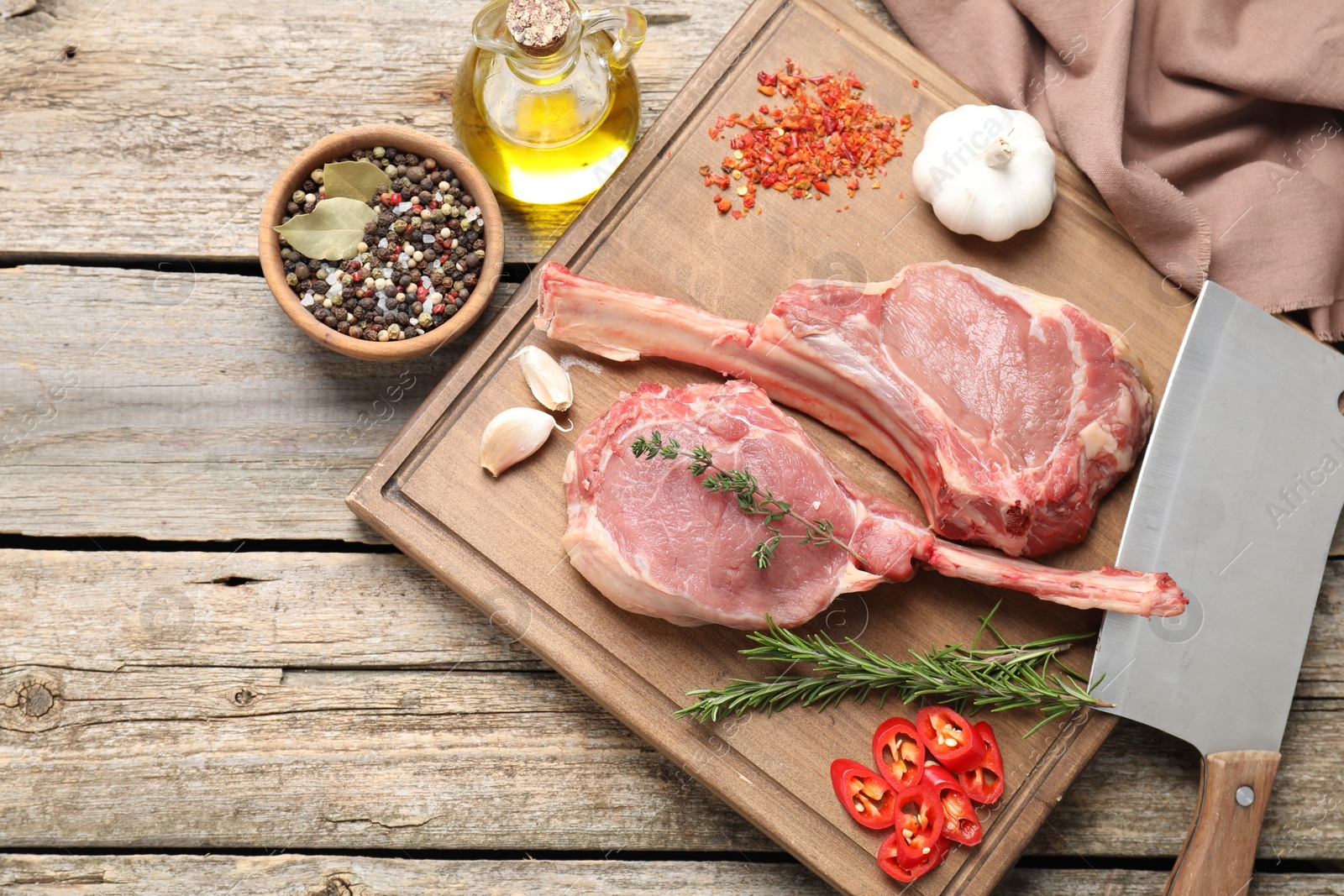 Photo of Fresh tomahawk beef cuts, butcher knife and spices on wooden table, top view. Space for text