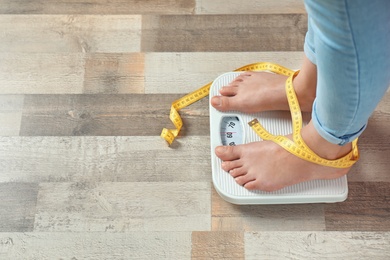 Woman with tied legs measuring her weight using scales on floor. Healthy diet