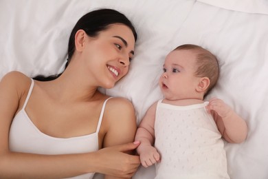 Young mother with her little baby on bed, top view