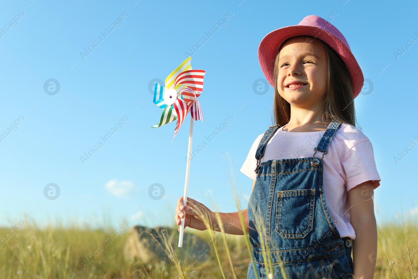 Photo of Cute little girl with pinwheel outdoors. Child spending time in nature