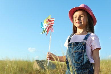 Photo of Cute little girl with pinwheel outdoors. Child spending time in nature
