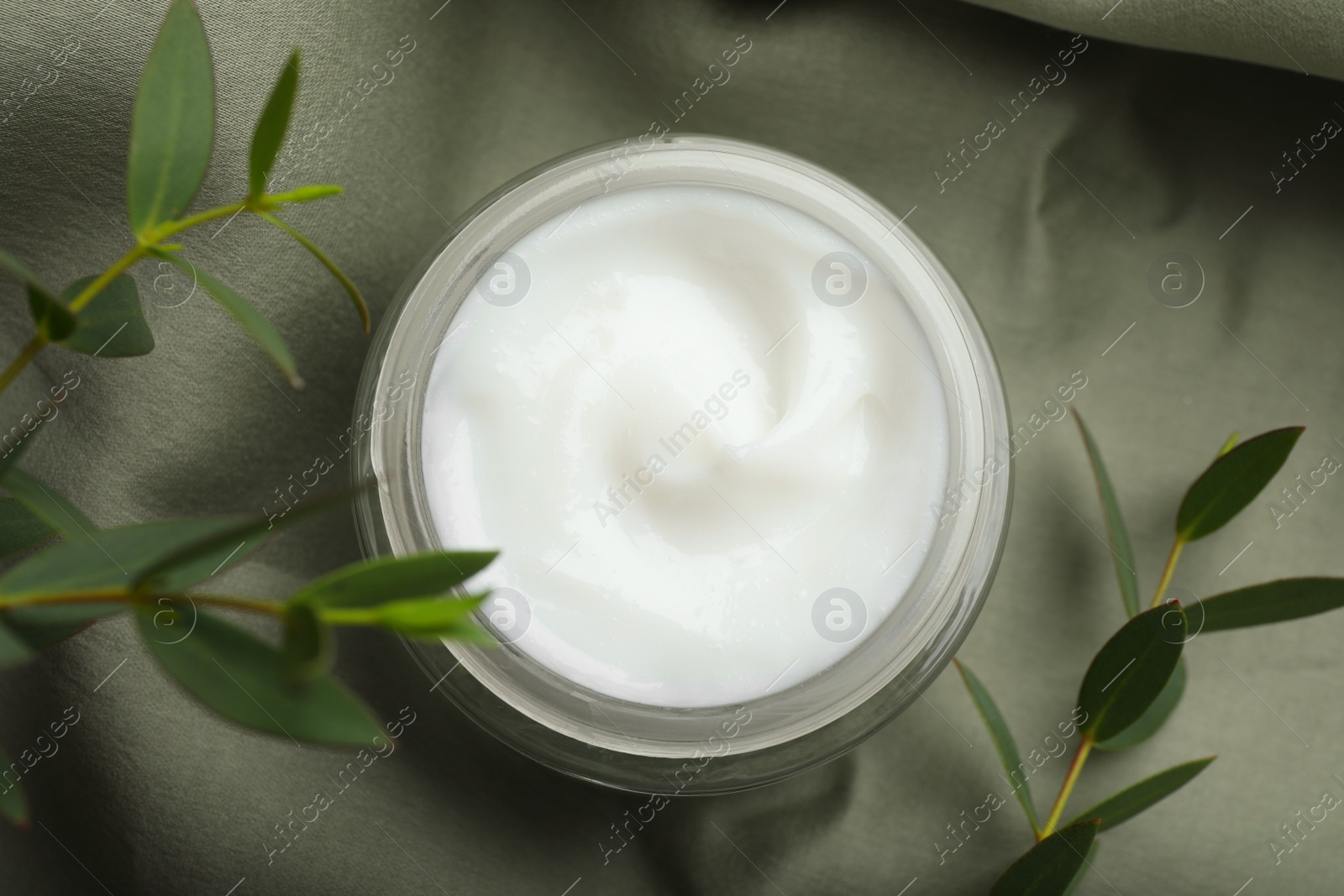 Photo of Jar of organic cream and eucalyptus on fabric, top view