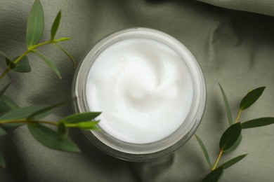 Photo of Jar of organic cream and eucalyptus on fabric, top view