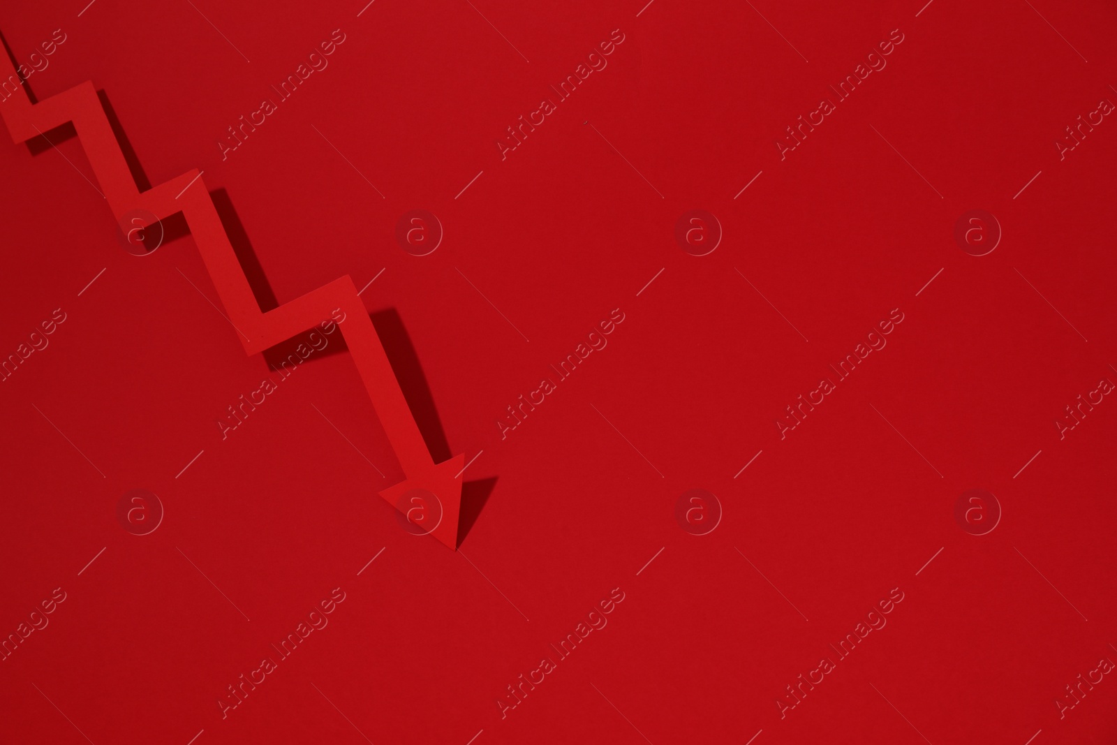 Photo of One zigzag paper arrow on red background, top view. Space for text