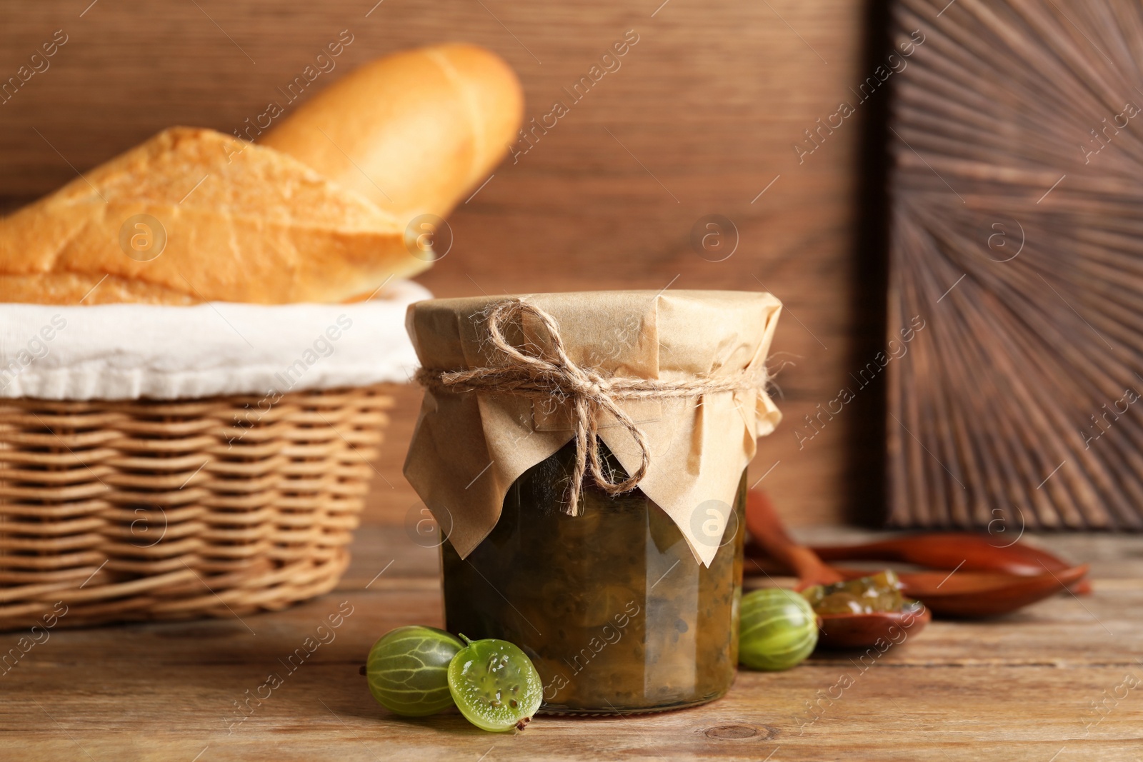 Photo of Jar of delicious gooseberry jam and fresh berries on wooden table