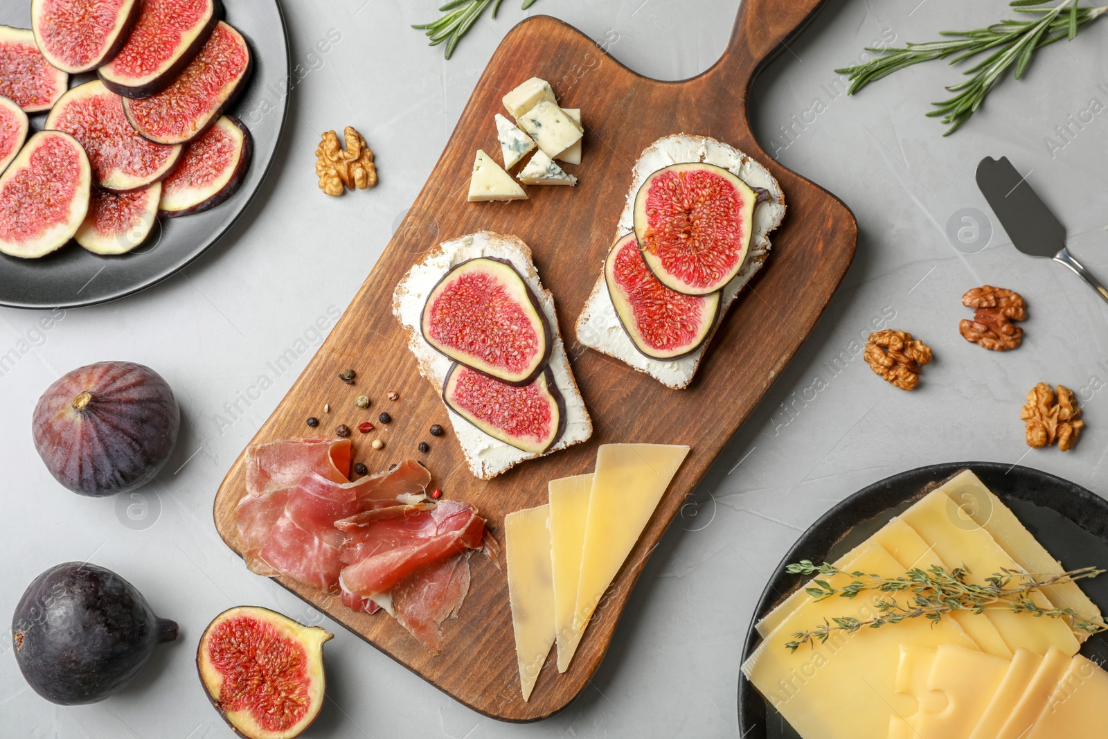 Photo of Sandwiches with ripe figs and delicious products on grey table, top view