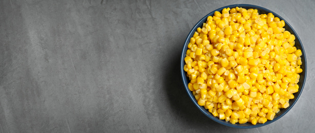 Delicious canned corn in bowl and space for text on grey table, top view. Banner design