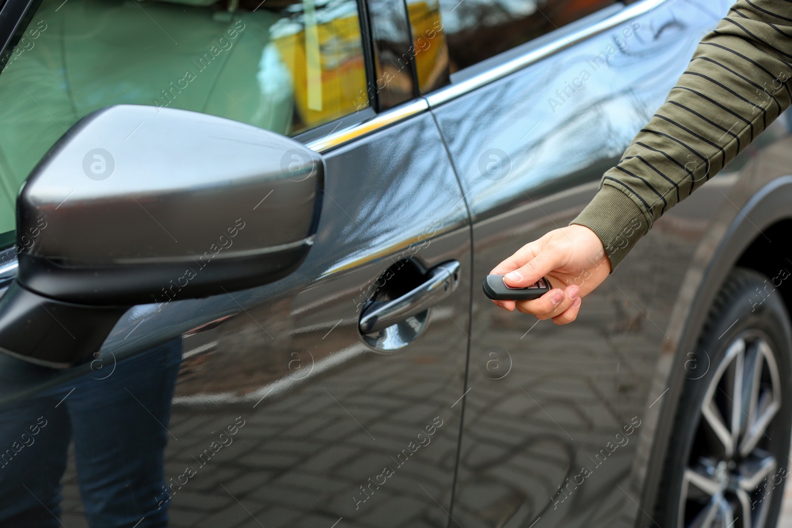 Photo of Closeup view of man opening car door with remote key