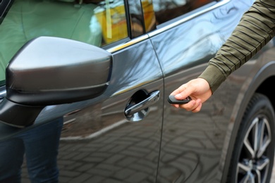 Closeup view of man opening car door with remote key