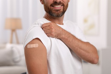 Photo of Man with sticking plaster on arm after vaccination at home, closeup