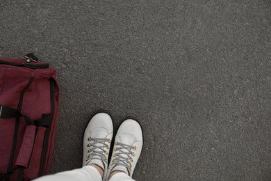 Photo of Woman with bag standing on asphalt, top view. Space for text