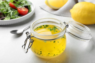 Photo of Jar with lemon sauce on light table. Delicious salad dressing