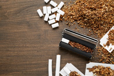 Photo of Flat lay composition with roller and tobacco on wooden table, space for text. Making hand rolled cigarettes