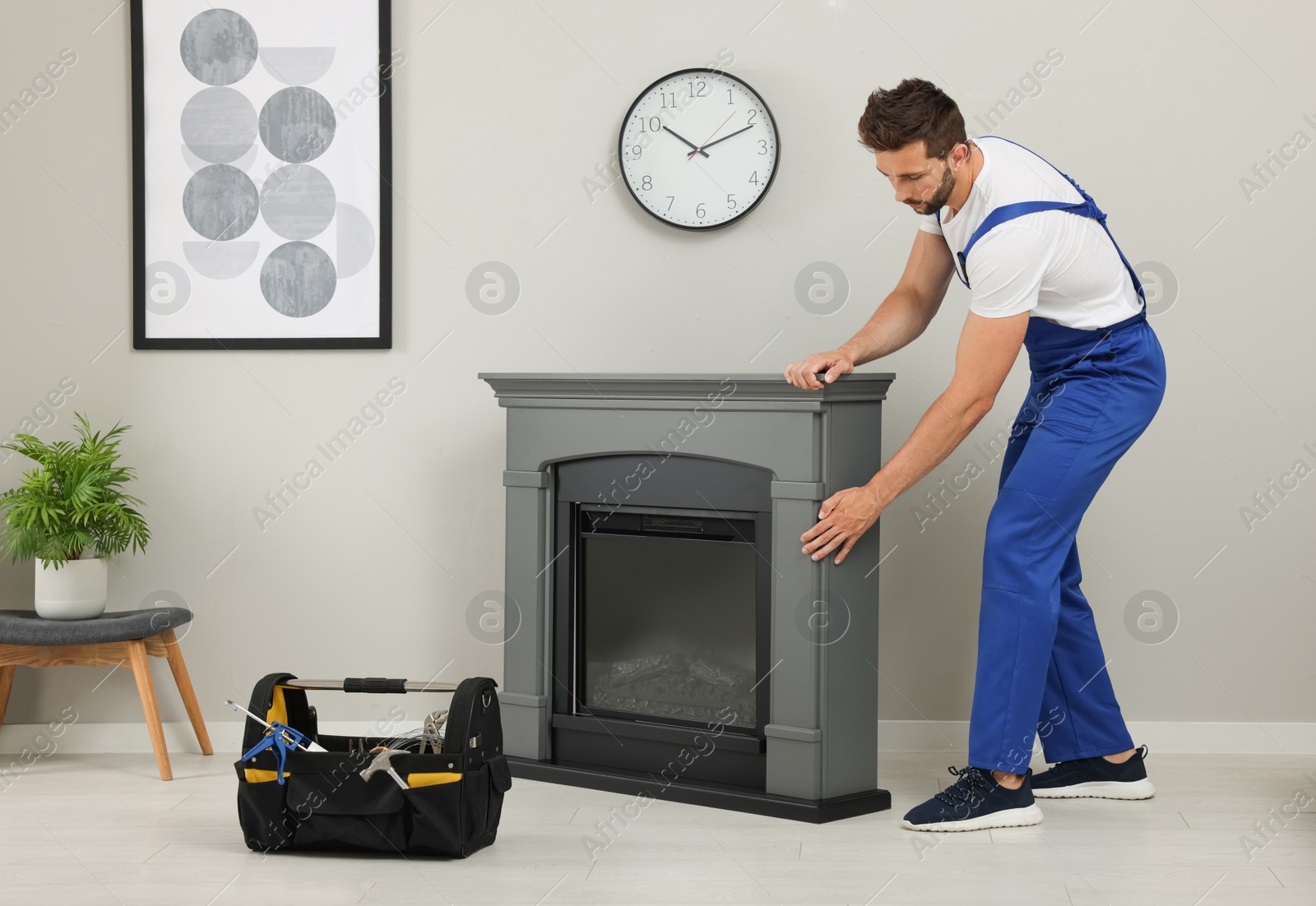 Photo of Professional technician installing electric fireplace in room