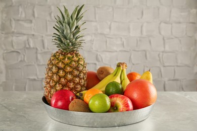 Tray with different ripe fruits on grey table