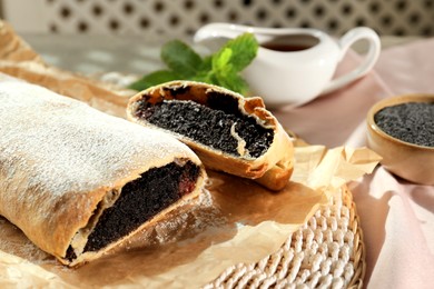 Photo of Delicious strudel with poppy seeds and cherries on mat, closeup