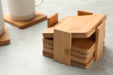 Stylish wooden cup coasters on light grey table