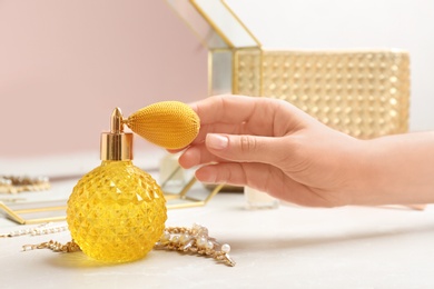 Photo of Woman reaching for crystal bottle of luxurious perfume on dressing table, closeup