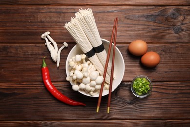 Cooking delicious ramen soup. Different ingredients and chopsticks on wooden table, flat lay