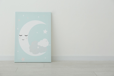Photo of Adorable picture of moon on floor near white wall, space for text. Children's room interior element