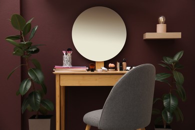 Wooden dressing table and chair near brown wall in room