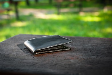 Photo of Black wallet on bench outdoors. Lost and found