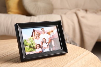 Photo of Frame with family photo on wooden table indoors. Space for text