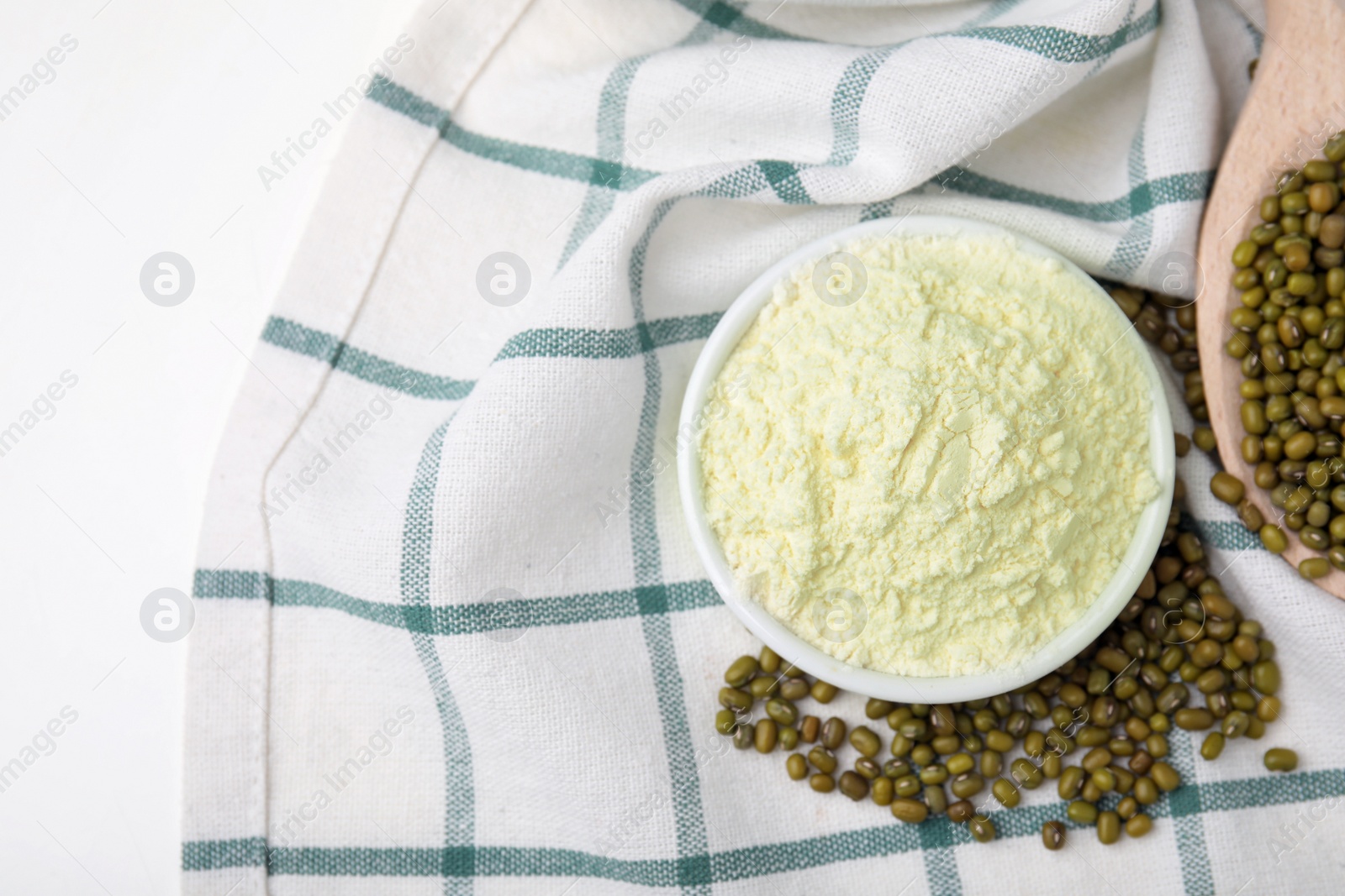 Photo of Bowl of flour and mung beans on cloth, flat lay. Space for text