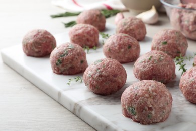 Many fresh raw meatballs on white wooden table, closeup
