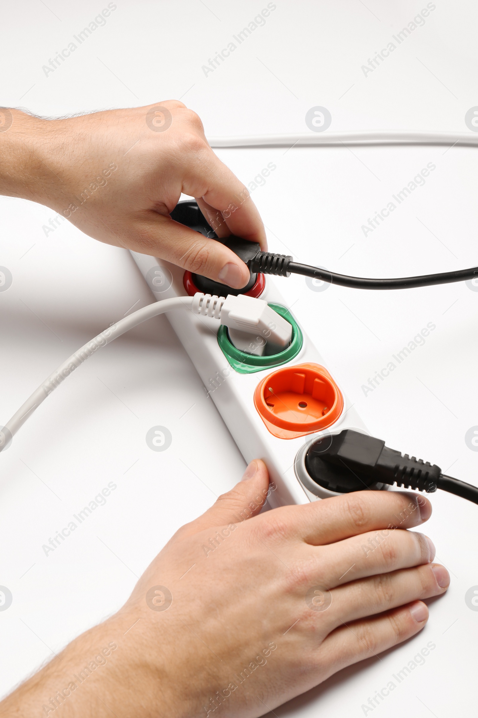 Photo of Man inserting power plug into extension cord on white background, closeup. Electrician's professional equipment