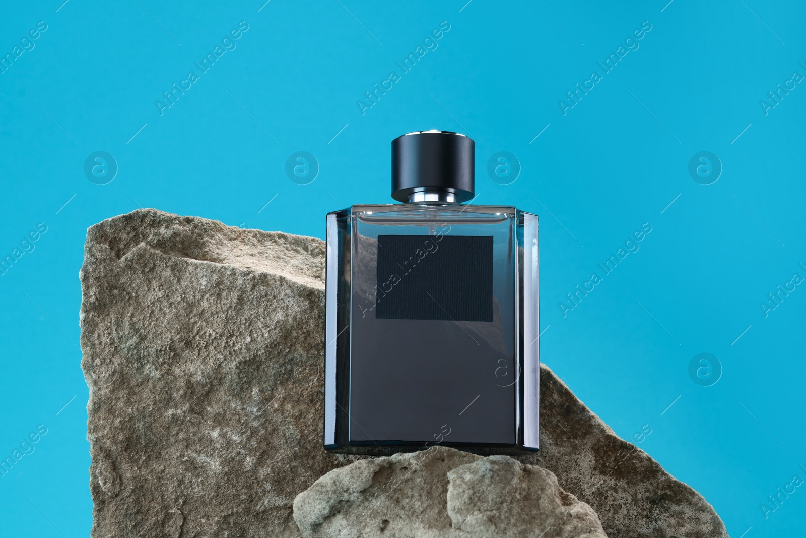 Photo of Stylish presentation of luxury men`s perfume on stones against light blue background