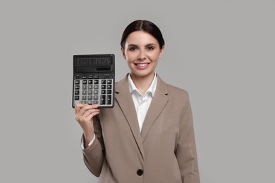 Photo of Smiling accountant with calculator on grey background