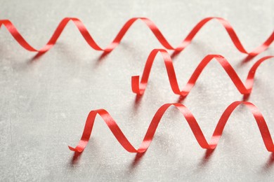 Photo of Shiny red serpentine streamers on grey background, closeup