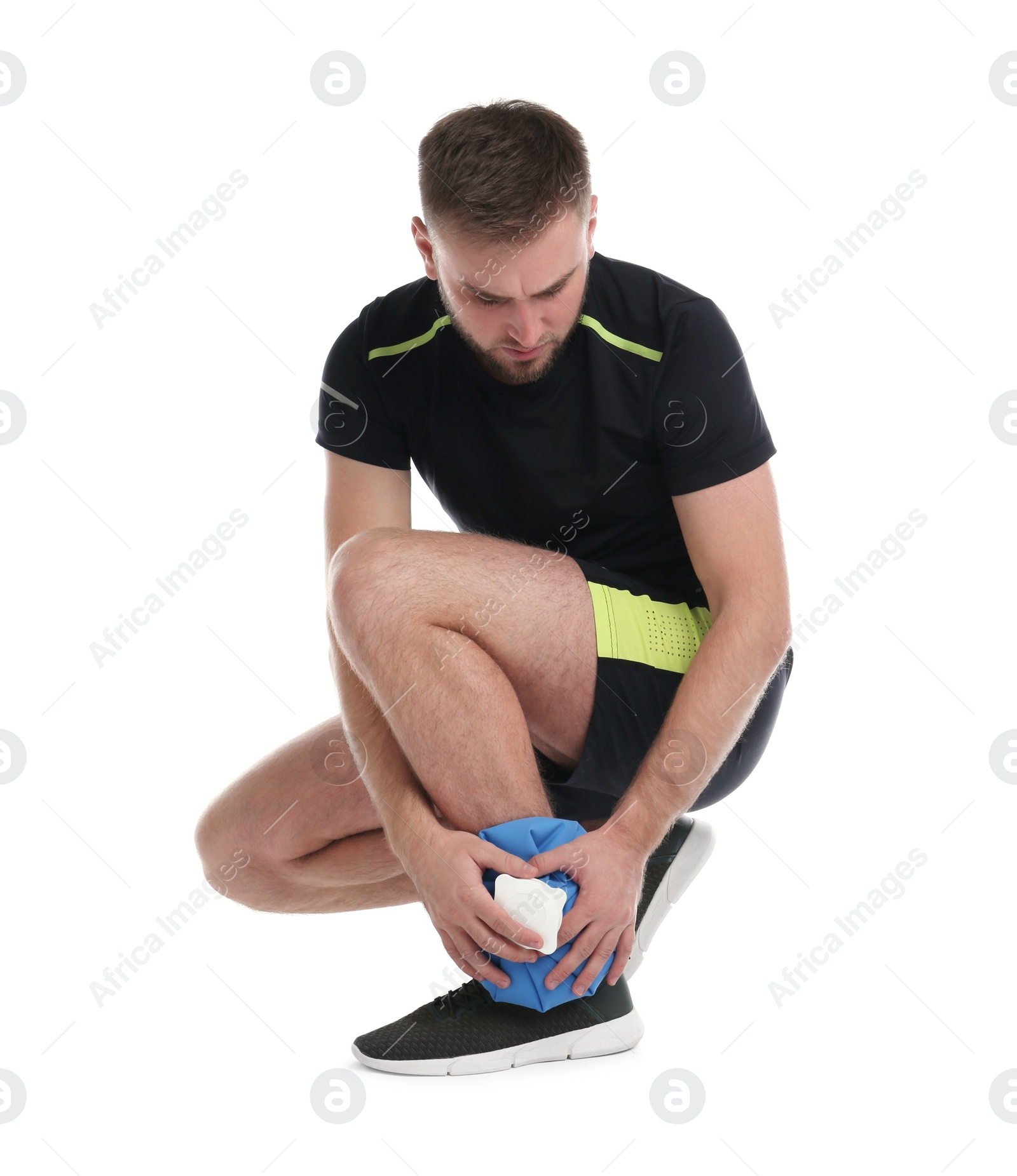 Photo of Young man with cold compress suffering from ankle pain on white background