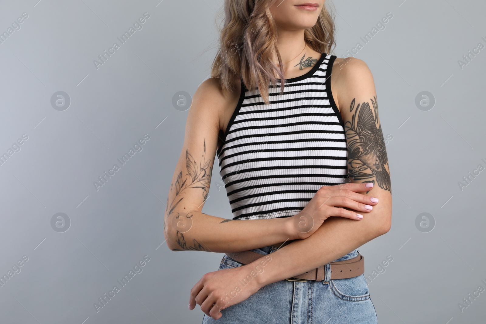 Photo of Beautiful woman with tattoos on body against grey background, closeup. Space for text