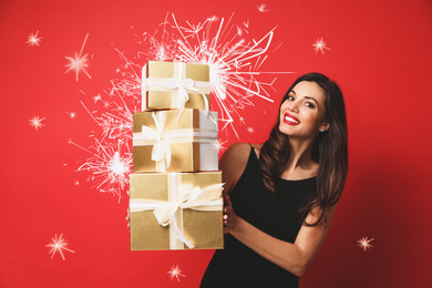 Image of Beautiful woman with Christmas gifts and sparklers on red background