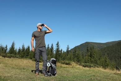 Photo of Tourist with backpack in mountains on sunny day. Space for text