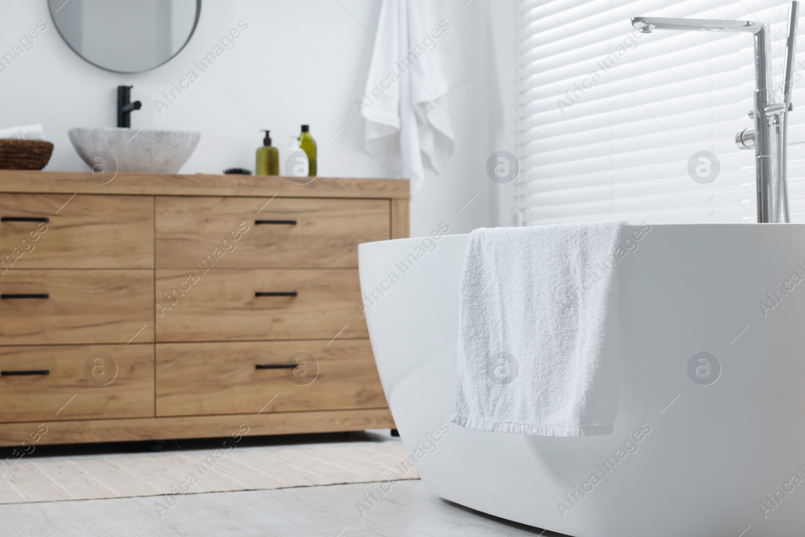 Photo of Soft bath towel on tub in bathroom. Space for text