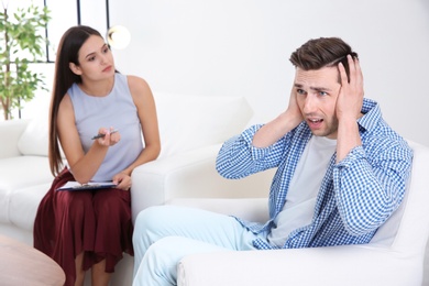 Depressed young man having appointment with psychologist in office