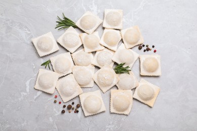 Photo of Uncooked ravioli, rosemary and peppercorns on grey marble table, flat lay