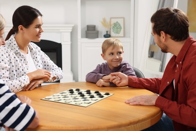 Family playing checkers in room. Father shaking hands with his son before game