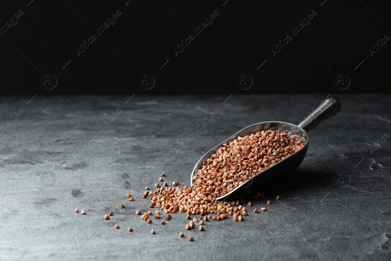 Photo of Buckwheat grains on grey table. Space for text