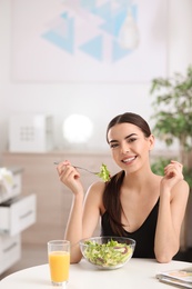 Photo of Young woman in fitness clothes having healthy breakfast at home