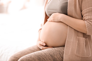 Photo of Young pregnant woman indoors, closeup