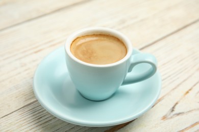 Cup of tasty coffee on white wooden table, closeup