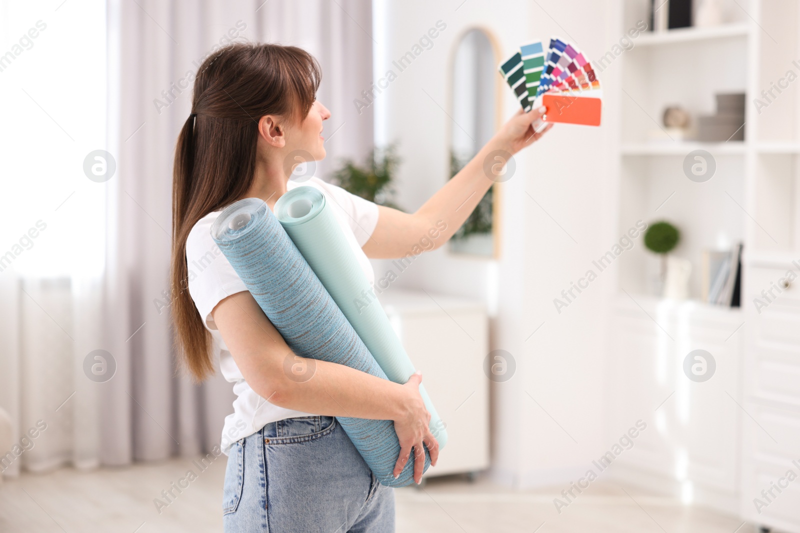 Photo of Woman with wallpaper rolls and color palette in room