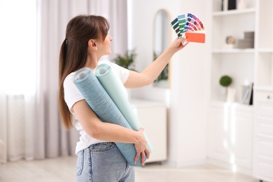 Woman with wallpaper rolls and color palette in room