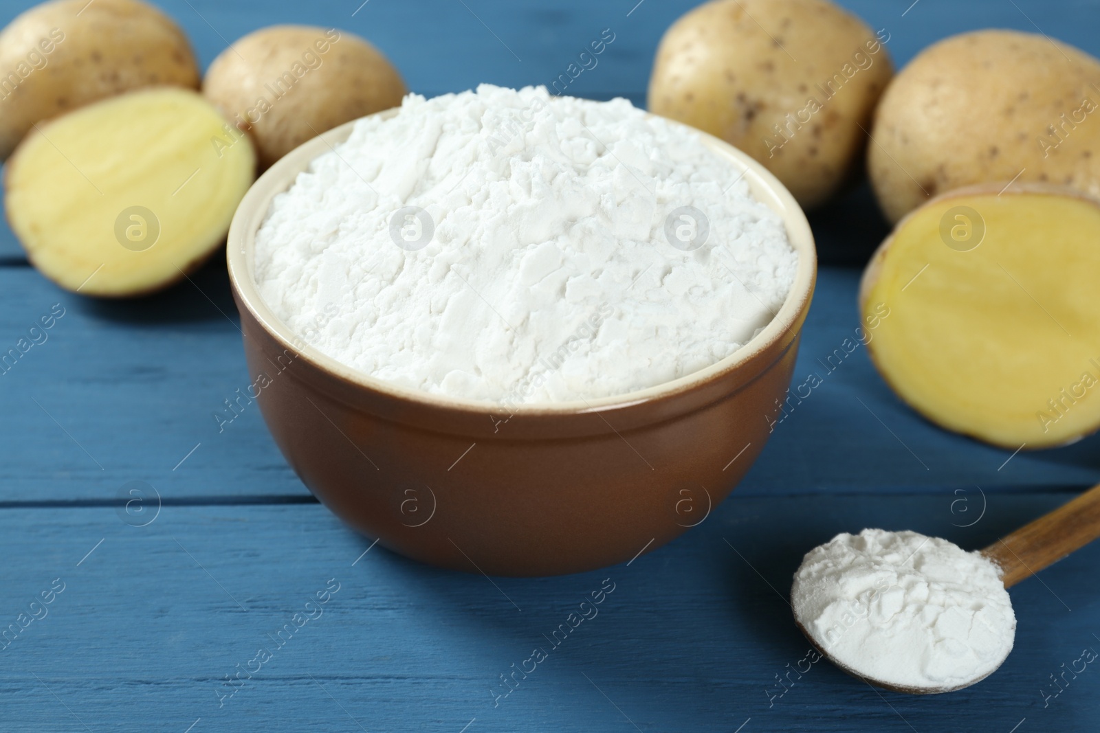 Photo of Starch and fresh potatoes on blue wooden table, closeup