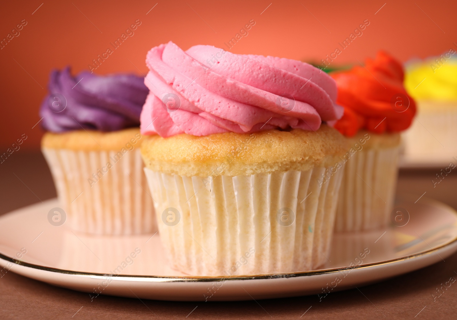 Photo of Delicious cupcakes with bright cream on color background, closeup